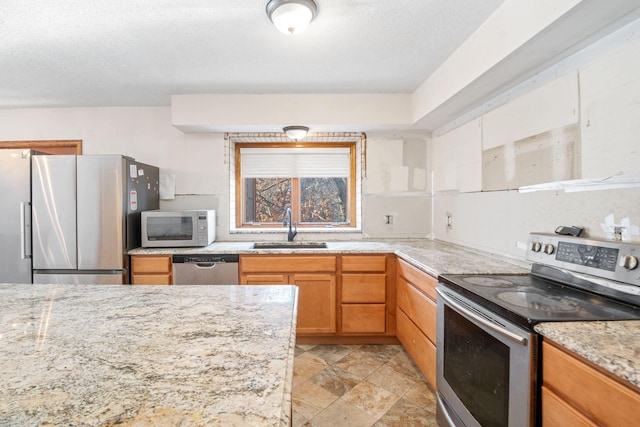 kitchen featuring appliances with stainless steel finishes, sink, a textured ceiling, and light stone counters