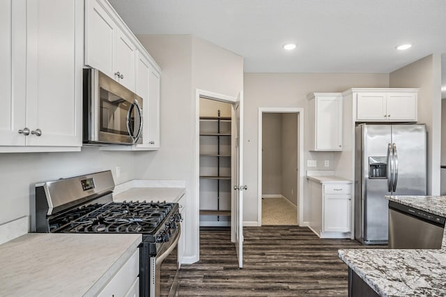 kitchen featuring dark wood-style floors, baseboards, appliances with stainless steel finishes, and white cabinets