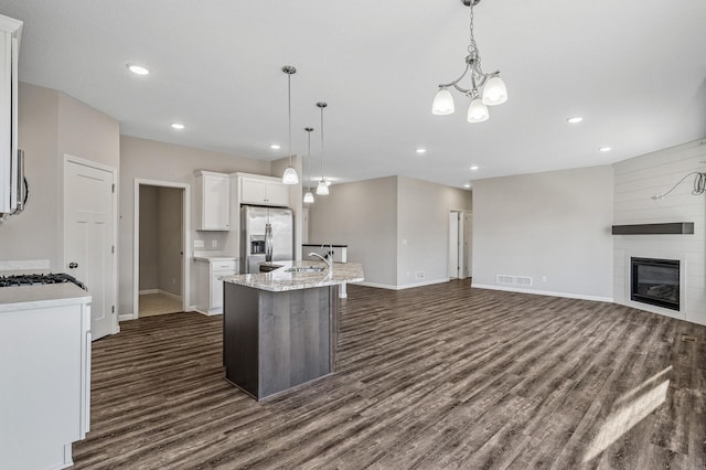 kitchen with visible vents, a large fireplace, dark wood-type flooring, stainless steel fridge with ice dispenser, and white cabinetry