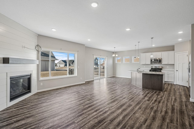 unfurnished living room featuring a sink, baseboards, a large fireplace, and dark wood-type flooring