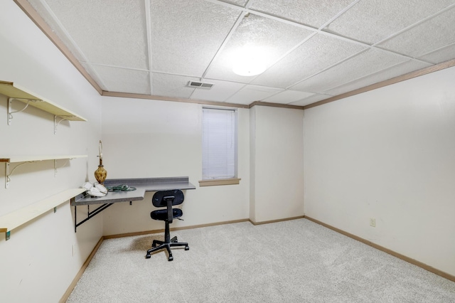 office space with a paneled ceiling, built in desk, and light carpet