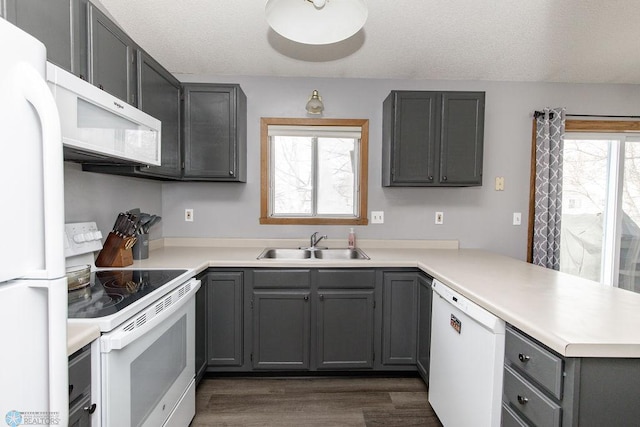 kitchen featuring sink, gray cabinetry, a textured ceiling, kitchen peninsula, and white appliances