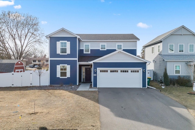 traditional home with aphalt driveway, a gate, fence, and a garage