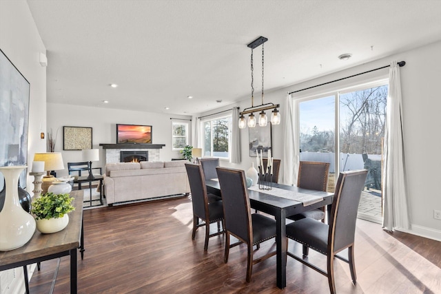 dining room featuring recessed lighting, wood finished floors, baseboards, and a lit fireplace