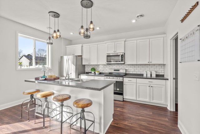 kitchen with dark countertops, backsplash, appliances with stainless steel finishes, and dark wood finished floors