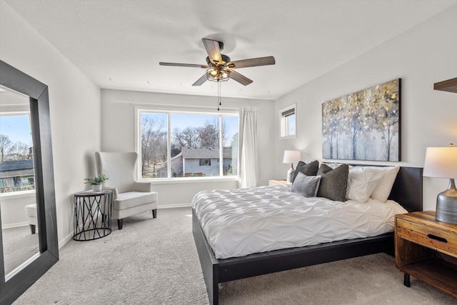 carpeted bedroom featuring multiple windows, a ceiling fan, and baseboards