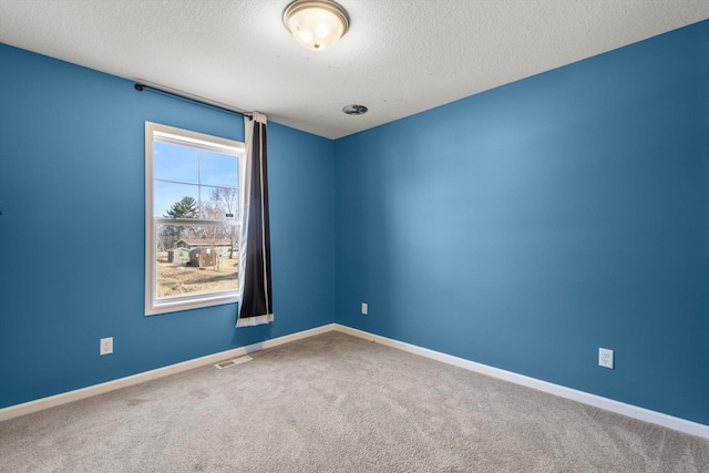 carpeted spare room with visible vents, a textured ceiling, and baseboards