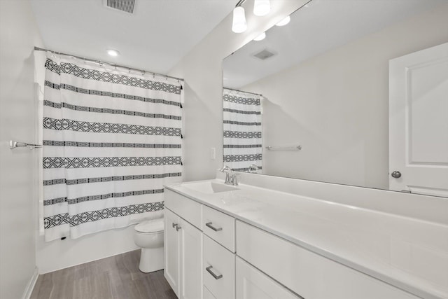 full bathroom featuring visible vents, toilet, wood finished floors, vanity, and shower / bathtub combination with curtain