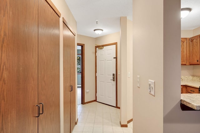 corridor with light tile patterned floors and a textured ceiling