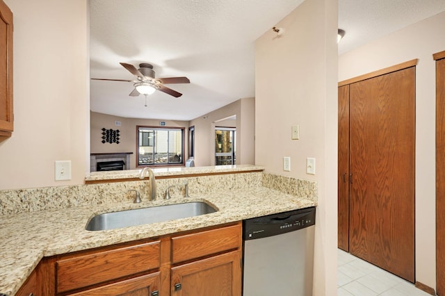 kitchen with sink, ceiling fan, light stone counters, stainless steel dishwasher, and kitchen peninsula