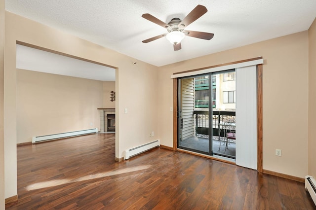 spare room with dark hardwood / wood-style flooring, a fireplace, and baseboard heating