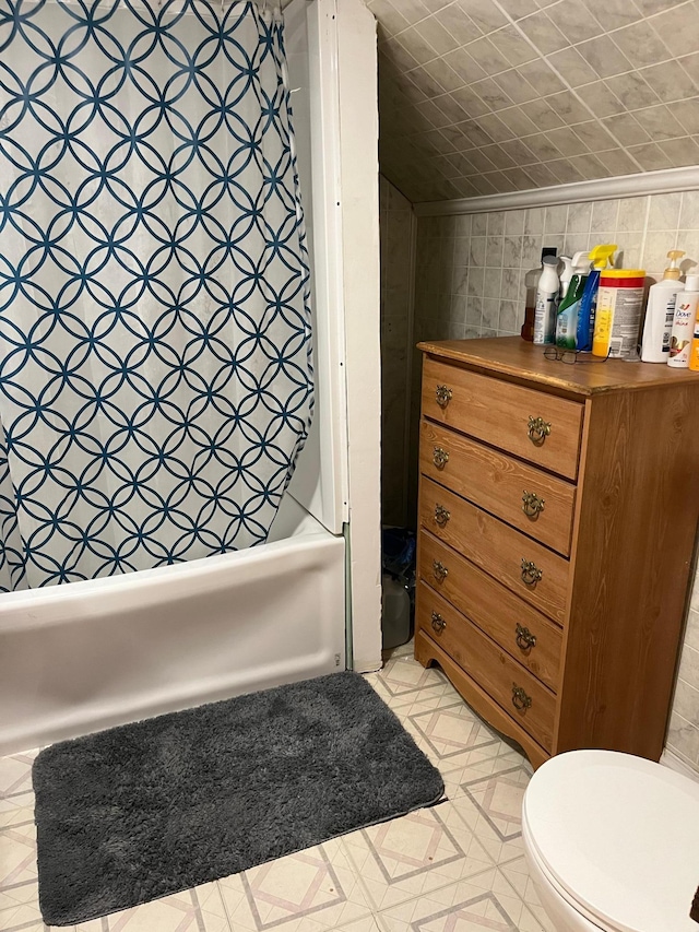 bathroom featuring shower / bath combination with curtain, toilet, and crown molding