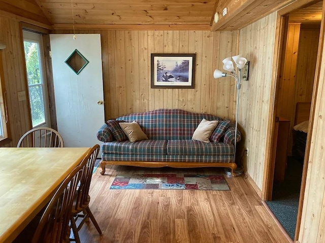 living area featuring vaulted ceiling, hardwood / wood-style floors, wooden ceiling, and wooden walls