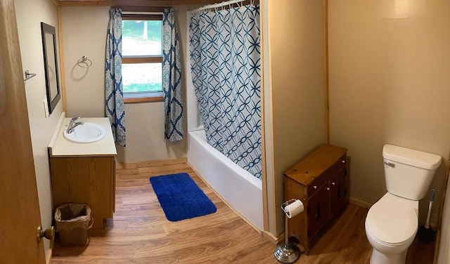 full bathroom with hardwood / wood-style flooring, shower / tub combo with curtain, vanity, and toilet