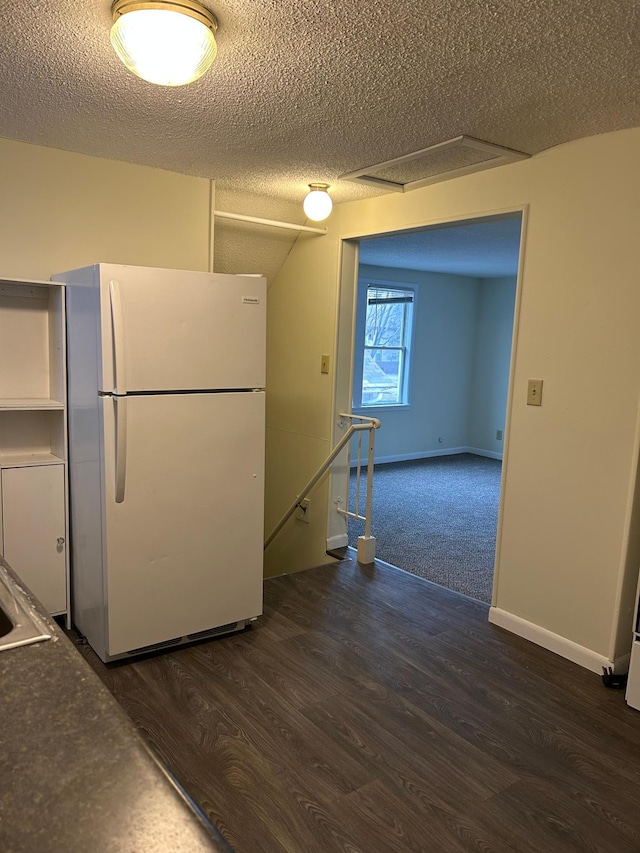 kitchen featuring white fridge, dark wood-type flooring, and a textured ceiling