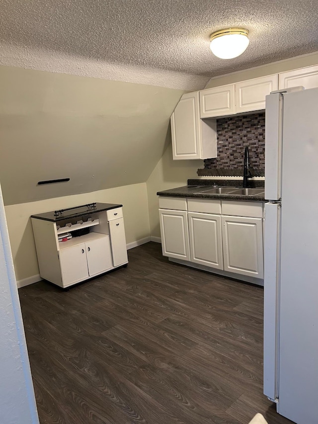 kitchen with lofted ceiling, sink, white cabinetry, dark hardwood / wood-style floors, and white refrigerator