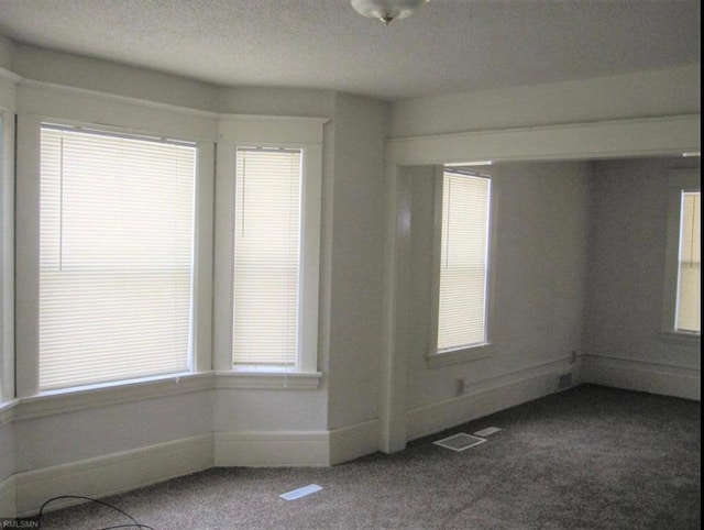 carpeted empty room featuring a textured ceiling