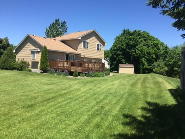 rear view of house featuring a storage shed, a yard, and a deck