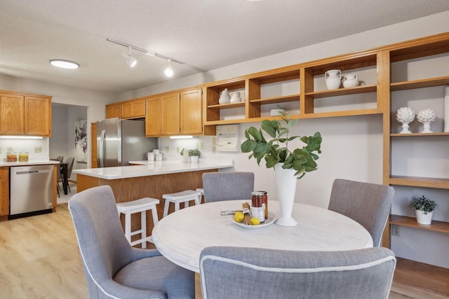 dining space with track lighting, light hardwood / wood-style floors, and a textured ceiling