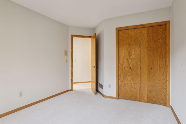 unfurnished bedroom with light colored carpet and a closet