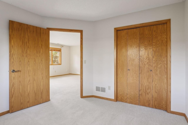 unfurnished bedroom featuring light colored carpet and a closet