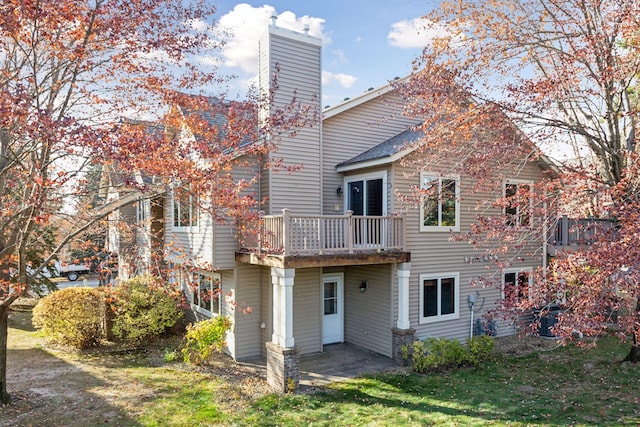 back of property featuring a wooden deck, a patio area, and a lawn