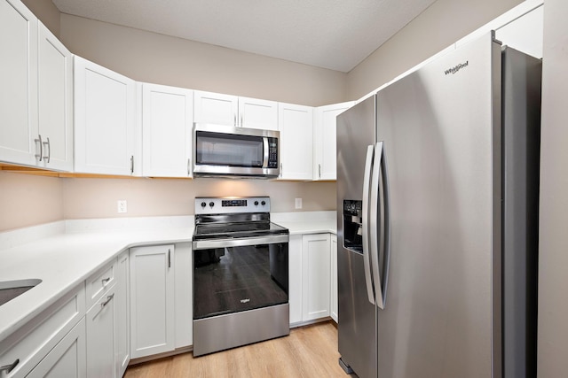 kitchen featuring appliances with stainless steel finishes, light hardwood / wood-style flooring, and white cabinets