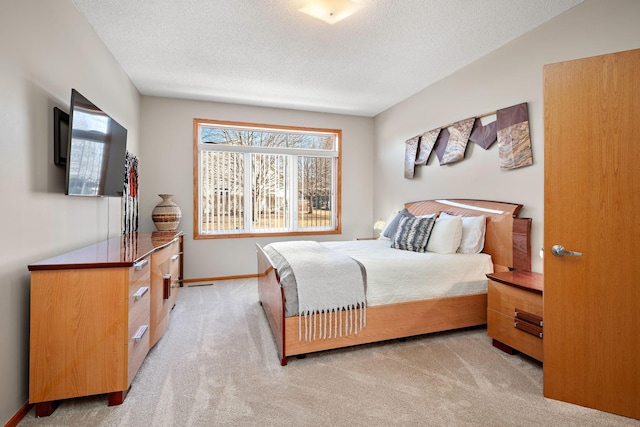 bedroom with light colored carpet and a textured ceiling