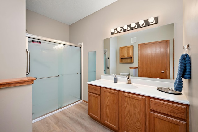 bathroom with wood-type flooring, vanity, an enclosed shower, and toilet