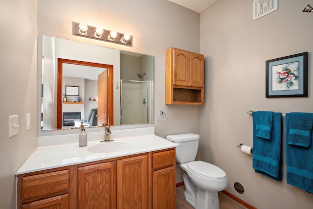 bathroom with a shower with door, vanity, and toilet