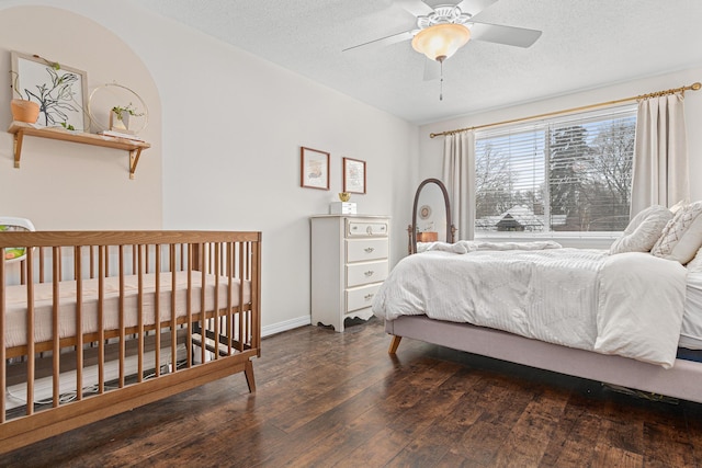 bedroom featuring ceiling fan, dark hardwood / wood-style floors, and a textured ceiling