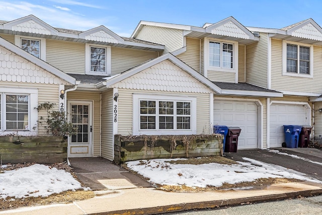 multi unit property with an attached garage, driveway, and a shingled roof