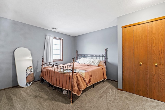 carpeted bedroom with visible vents, baseboards, and a closet