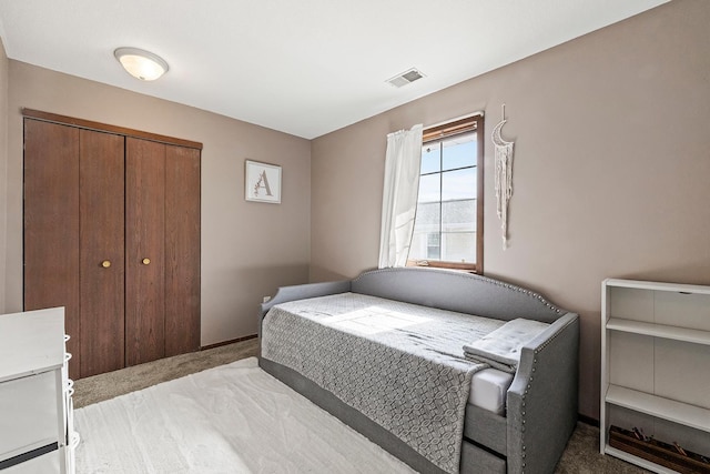 bedroom with a closet, visible vents, and light colored carpet