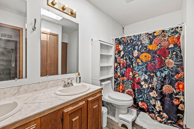 full bath with visible vents, toilet, double vanity, a skylight, and a sink