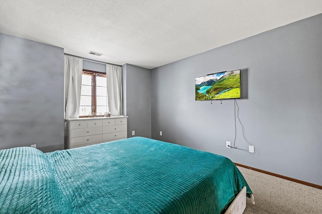 carpeted bedroom featuring baseboards, visible vents, and a textured ceiling