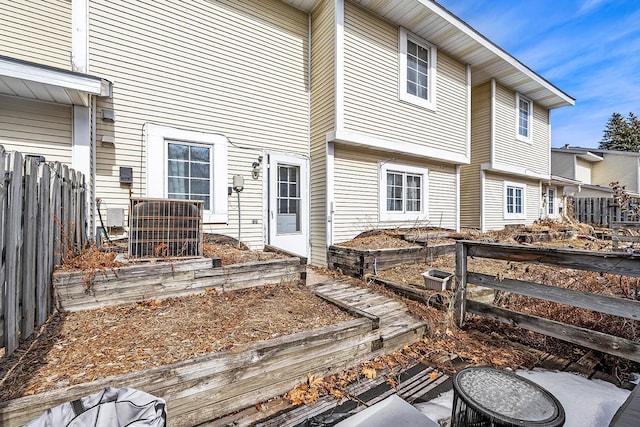 back of house with central air condition unit, a vegetable garden, and fence