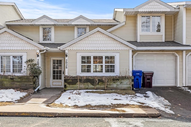 townhome / multi-family property featuring an attached garage, driveway, and a shingled roof