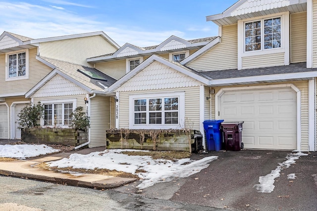 view of front of house featuring aphalt driveway, an attached garage, and a shingled roof