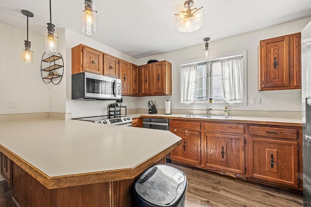 kitchen with stainless steel microwave, a sink, a peninsula, light countertops, and brown cabinetry