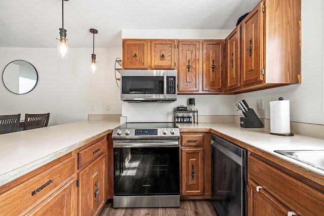 kitchen featuring stainless steel appliances, brown cabinetry, light countertops, decorative light fixtures, and dark wood-style floors