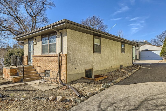 view of side of home with an outbuilding, brick siding, a garage, and stucco siding