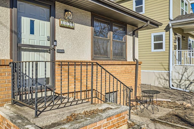 doorway to property with stucco siding and brick siding