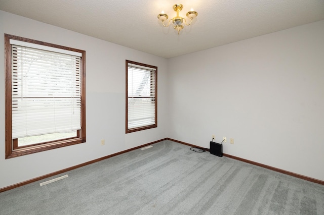 carpeted empty room with a chandelier