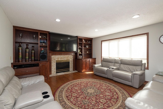 living room featuring dark hardwood / wood-style flooring, a brick fireplace, and a textured ceiling