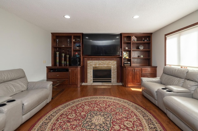 living room with a brick fireplace, hardwood / wood-style flooring, and a textured ceiling