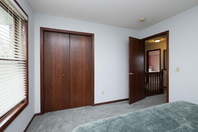 unfurnished bedroom featuring light colored carpet, a closet, and a textured ceiling