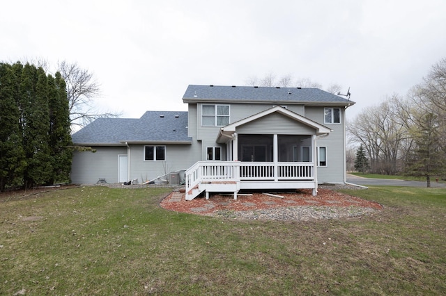 back of property with a deck, a sunroom, and a lawn