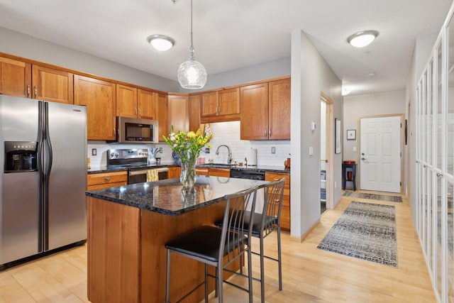 kitchen with a breakfast bar area, a kitchen island, a sink, appliances with stainless steel finishes, and tasteful backsplash