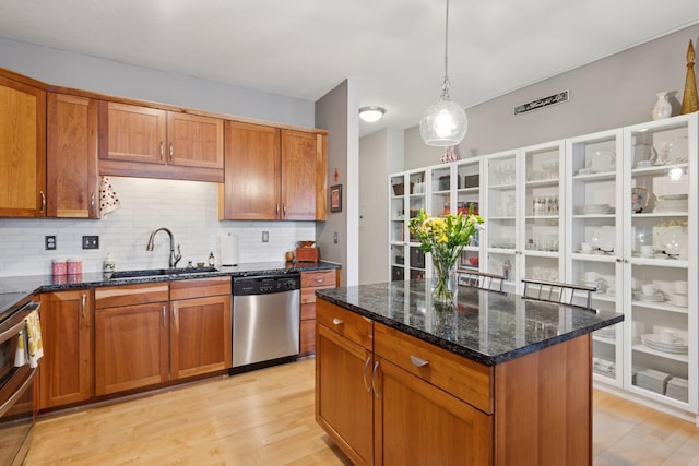 kitchen with appliances with stainless steel finishes, brown cabinetry, a sink, and light wood-style flooring